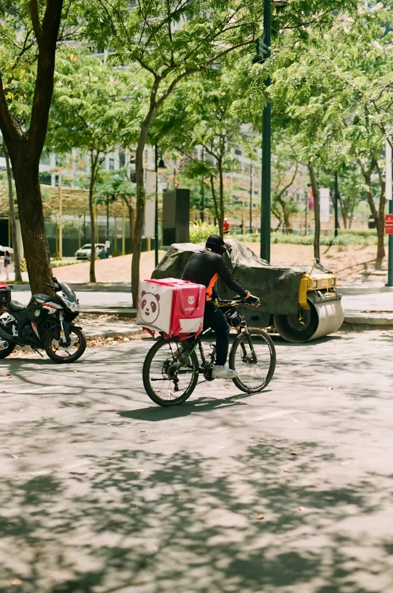 man in gray jacket riding on black and red motorcycle during daytime delivering Foodpanda order